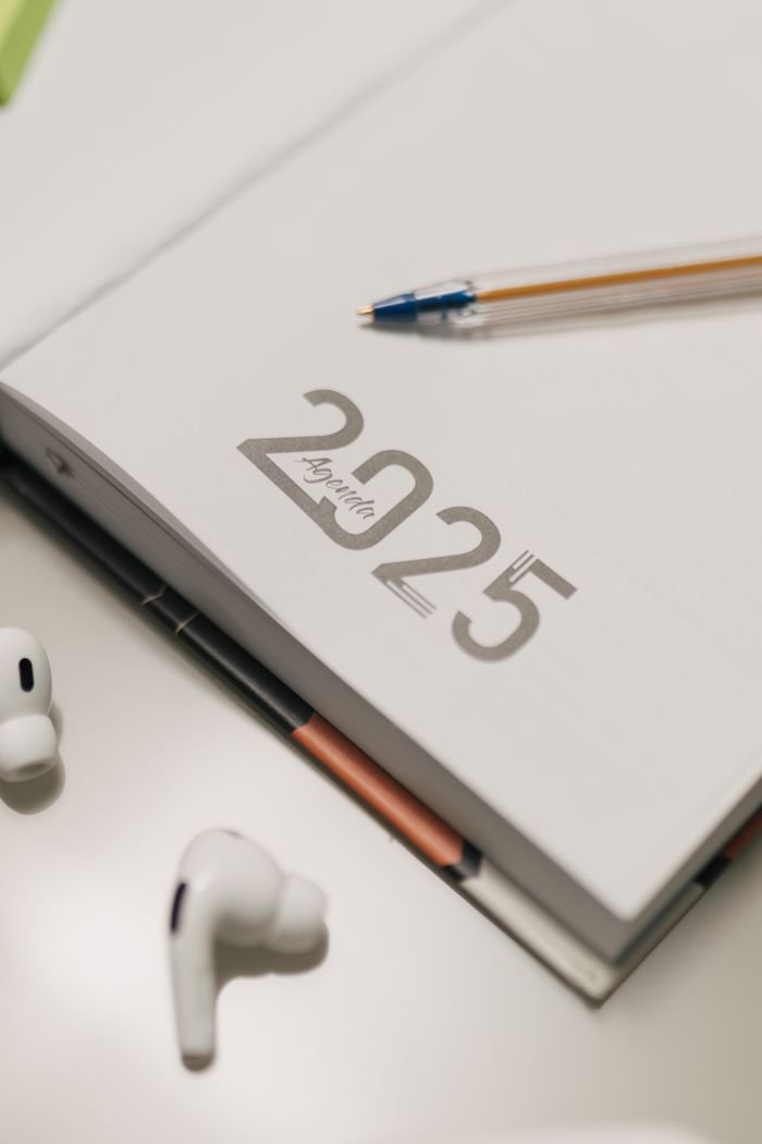 Mastering the First Impression: Your intriguing post title goes here Close-up of 2025 planner with AirPods and pen on desk.